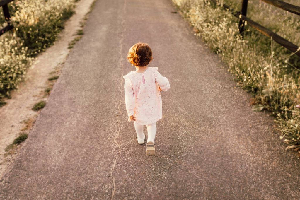 Little girl walks on a paved path