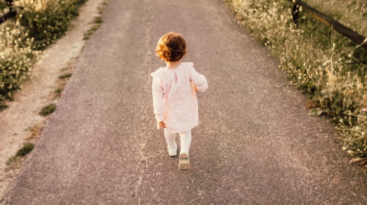 Little girl walks on a paved path