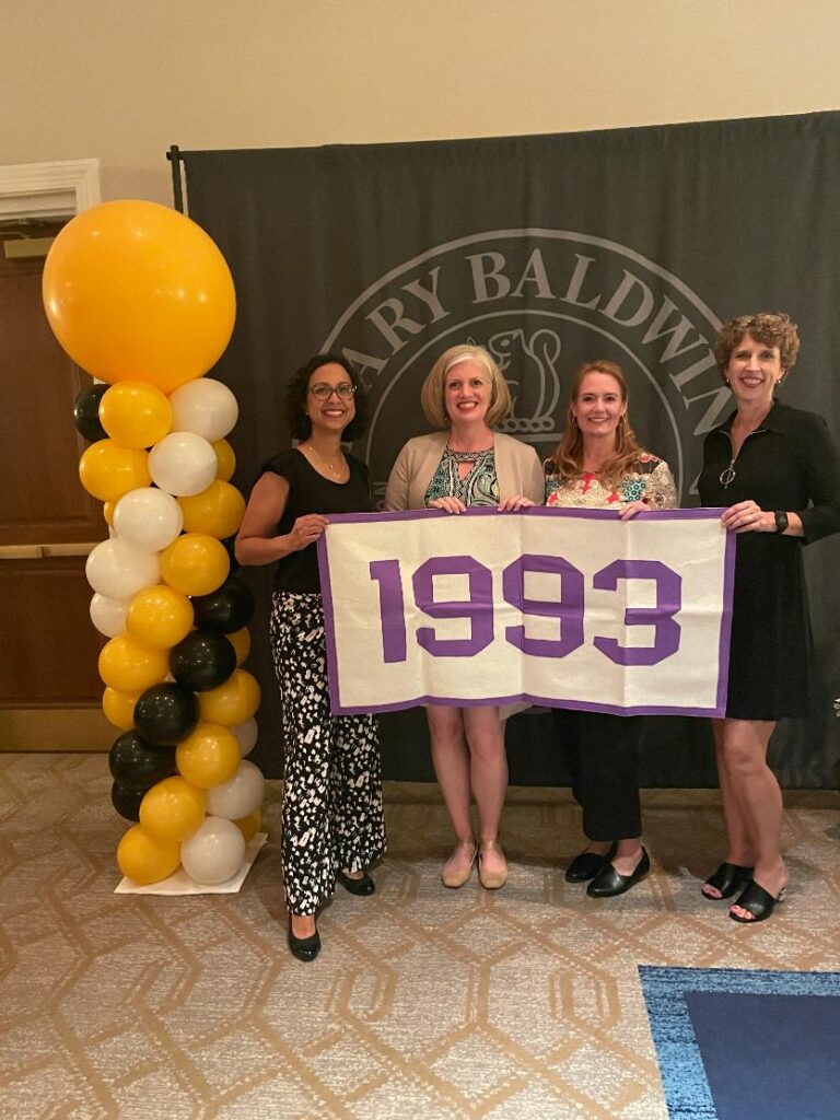 4 women hold banner with 1993 on it