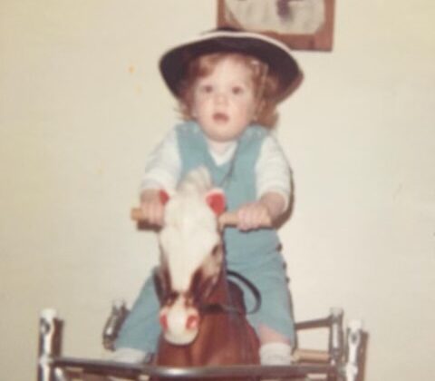 toddler wearing a cowboy hat on a play horse