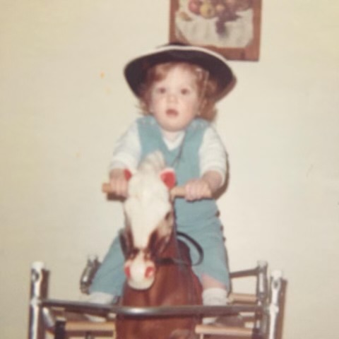 toddler wearing a cowboy hat on a play horse