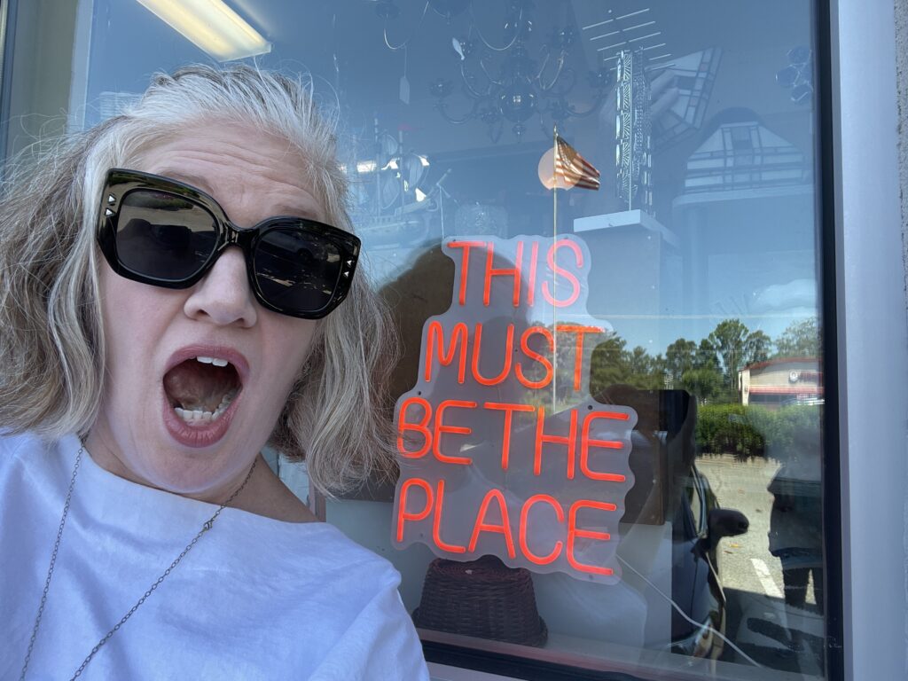 Emily next to sign that reads "this is the place"