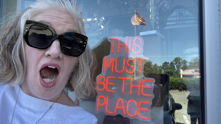 Emily next to sign that reads "this is the place"