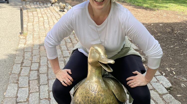 Emily sits on a brass statue of a duck in Boston