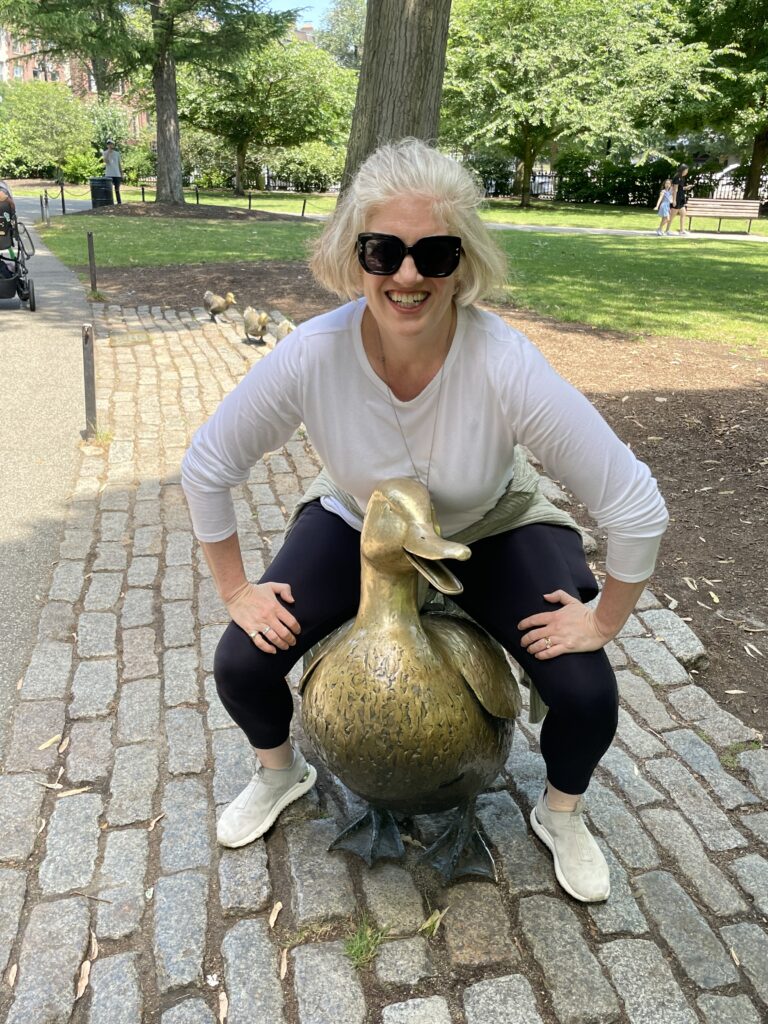 Emily sits on a brass statue of a duck in Boston