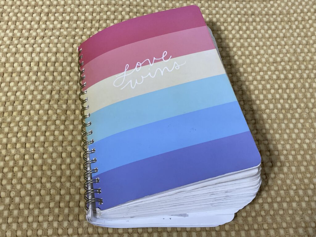 Spiral-bound notebook with "love wins" on the cover