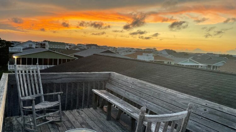 Rocking chairs on a roof top with a sunset in the sky